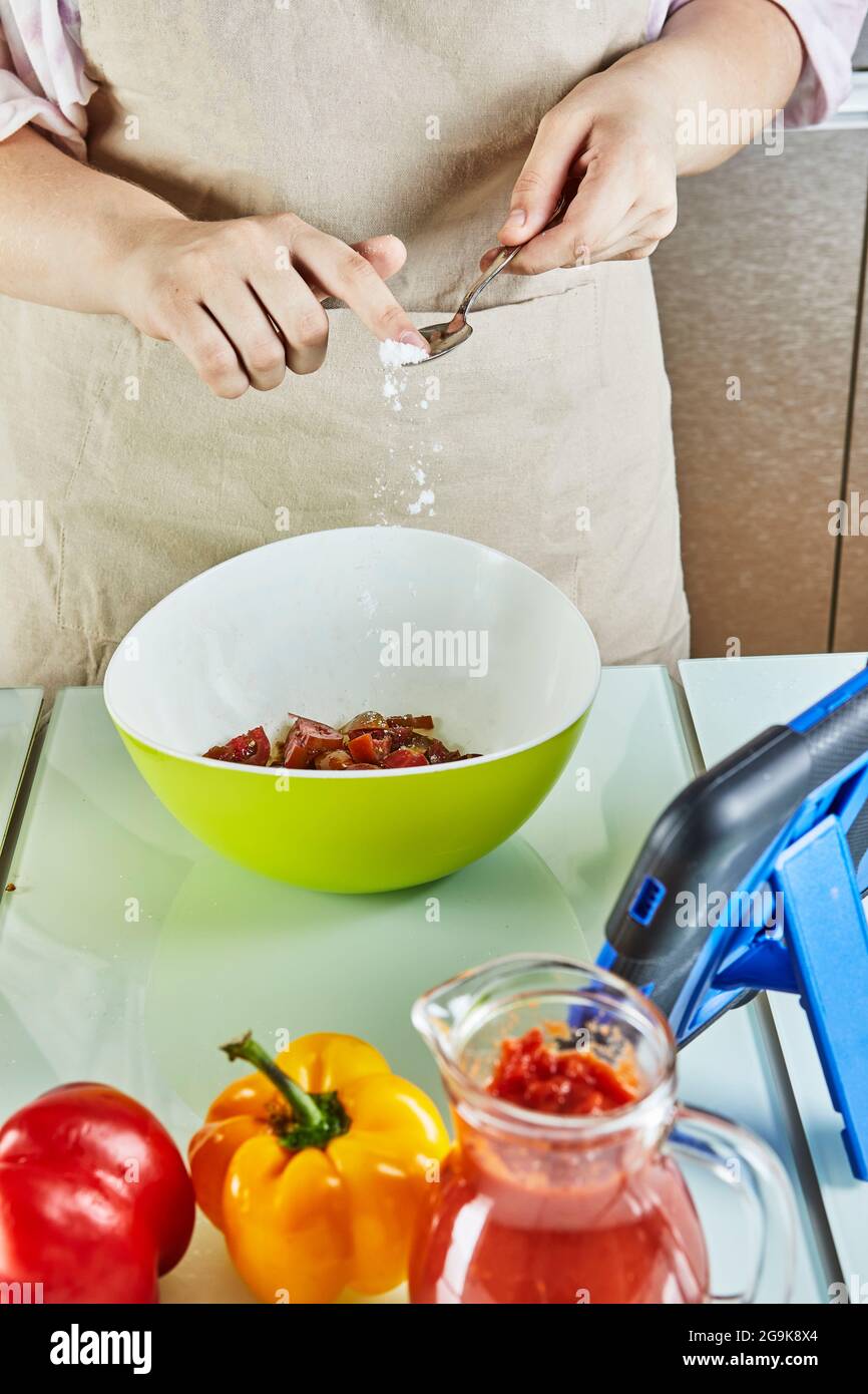Sale adolescente all'insalata utilizzando una guida online e visualizza la ricetta digitale sul tablet touch mentre si prepara un pasto sano in cucina a casa Foto Stock