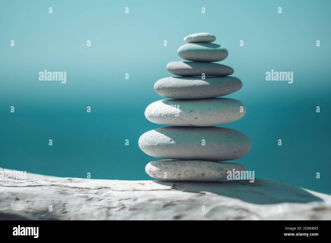 Equilibrata piramide di ciottoli sulla spiaggia in una giornata di sole. Abstract Sea bokeh sullo sfondo. Messa a fuoco selettiva. Pietre Zen sulla spiaggia di mare, meditazione Foto Stock