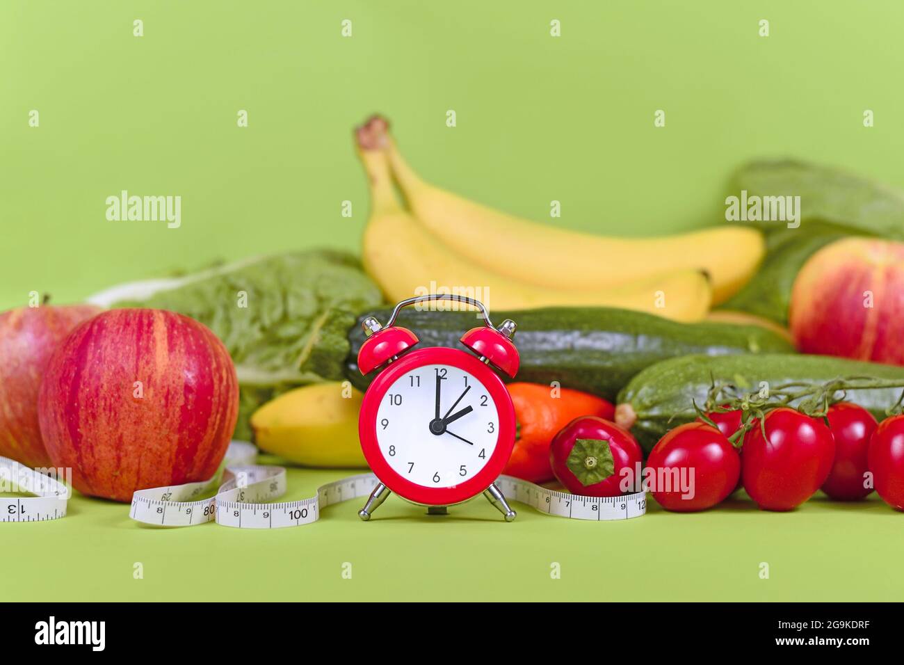 Concetto di dieta per perdere peso con solo mangiare cibo sano in determinati momenti con verdure, frutta, metro a nastro e orologio Foto Stock