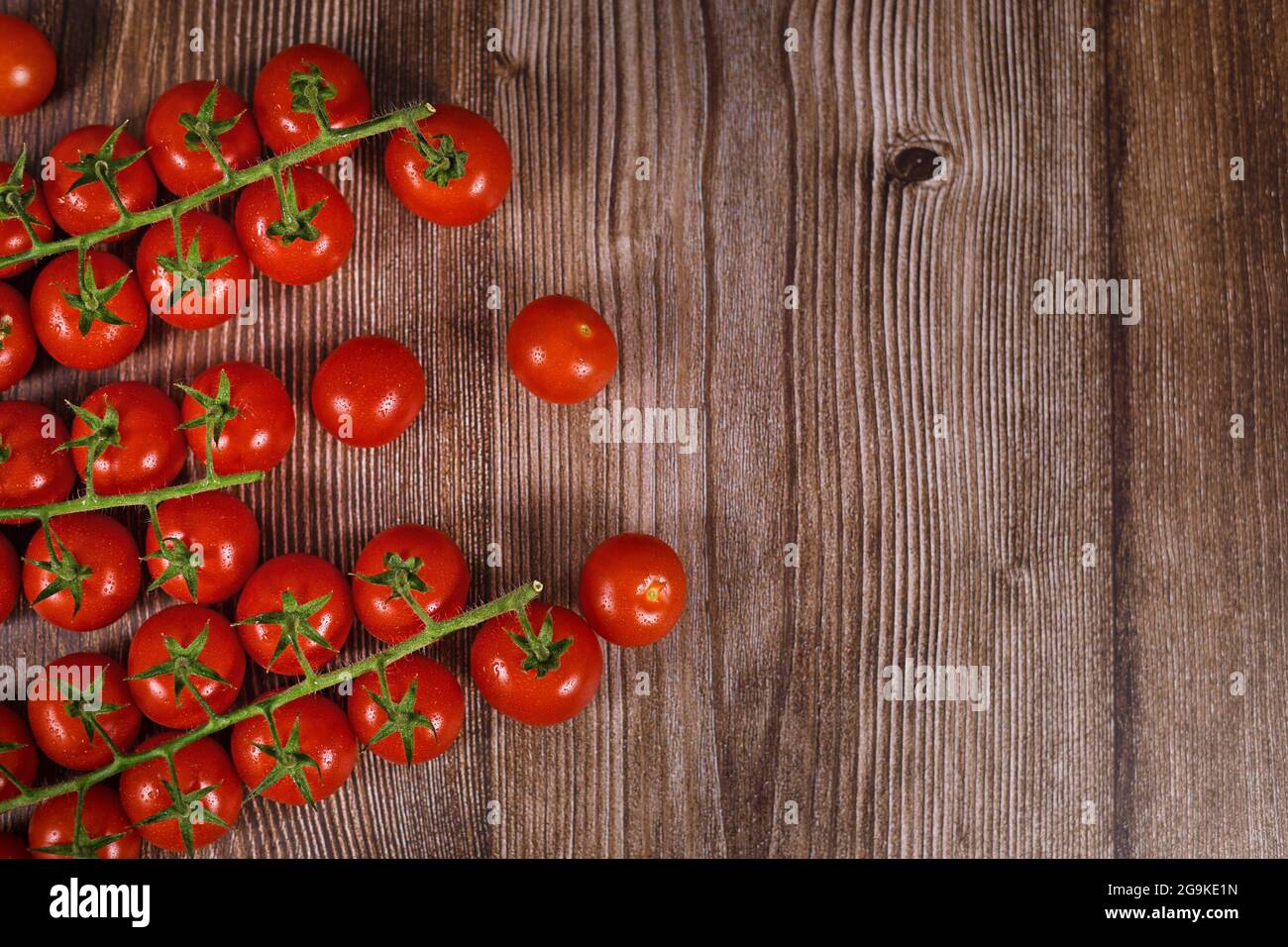 Capriate di piccoli pomodori ciliegini su fondo di legno con spazio di copia Foto Stock