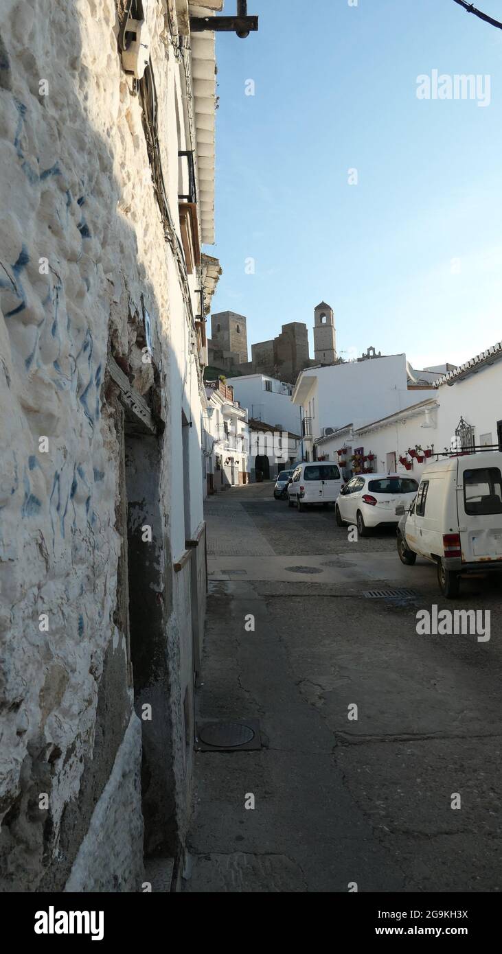 Stretta strada del villaggio che conduce al castello arabo fiancheggiato da automobili Foto Stock