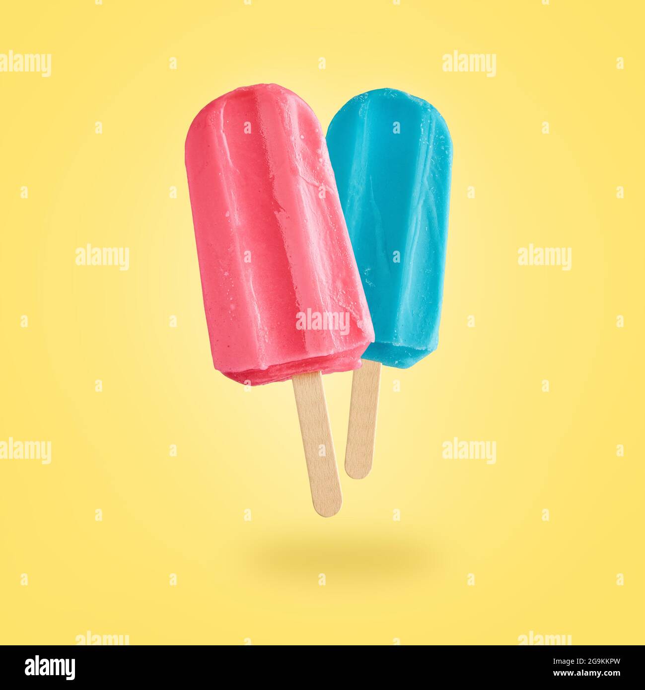 Gelati rossi e blu che volano su sfondo giallo con spazio per la copia. Sfondo estivo Foto Stock