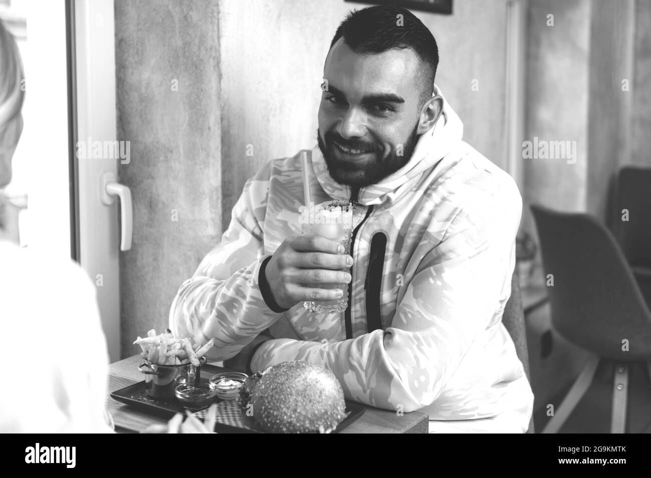 Ritratto di giovane coppia mangiare hamburger al ristorante e cocktail Passione frutta Mojito Foto Stock