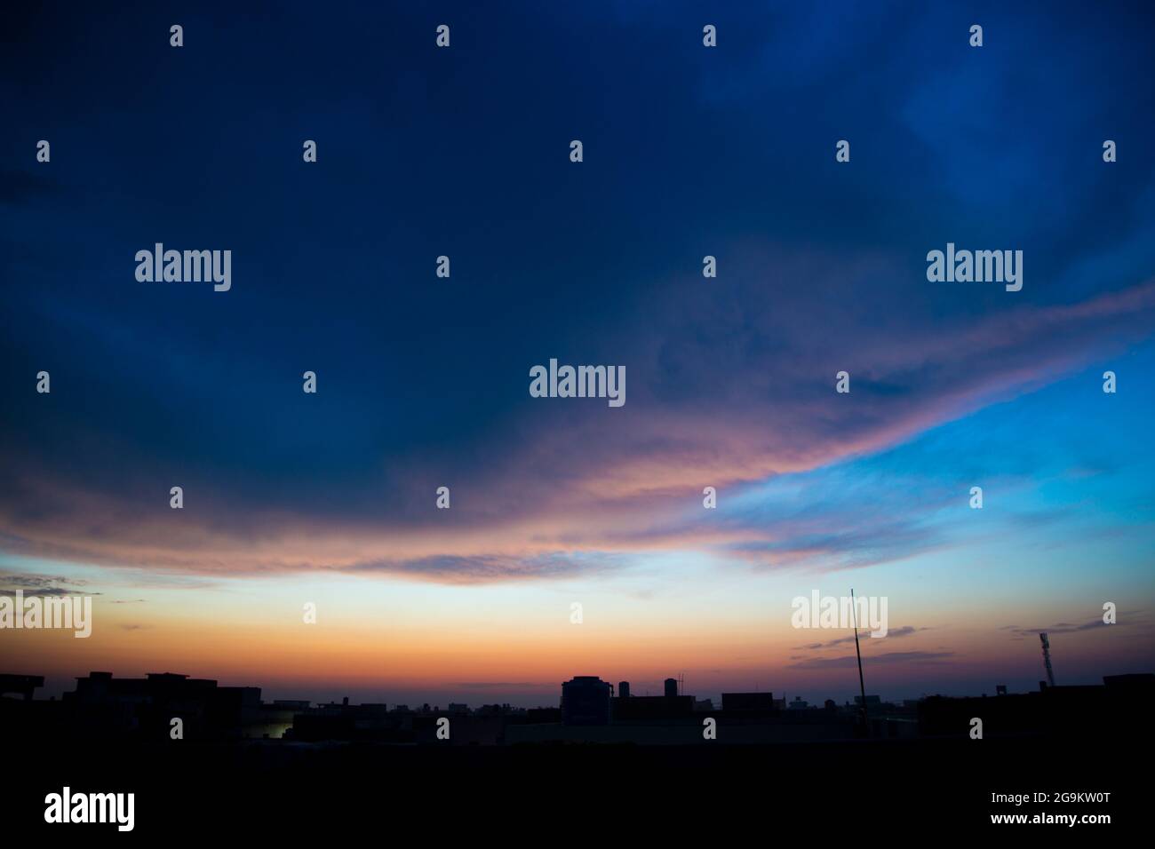 Alba cielo blu drammatico con raggi di sole arancio che si infrangono attraverso le nuvole. Natura sfondo. Concetto di speranza Foto Stock