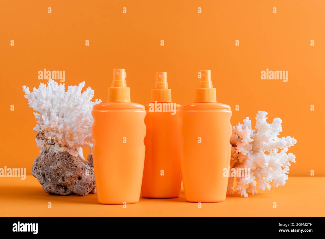 contenitori con protezione solare vicino ai coralli marini isolati su arancione Foto Stock