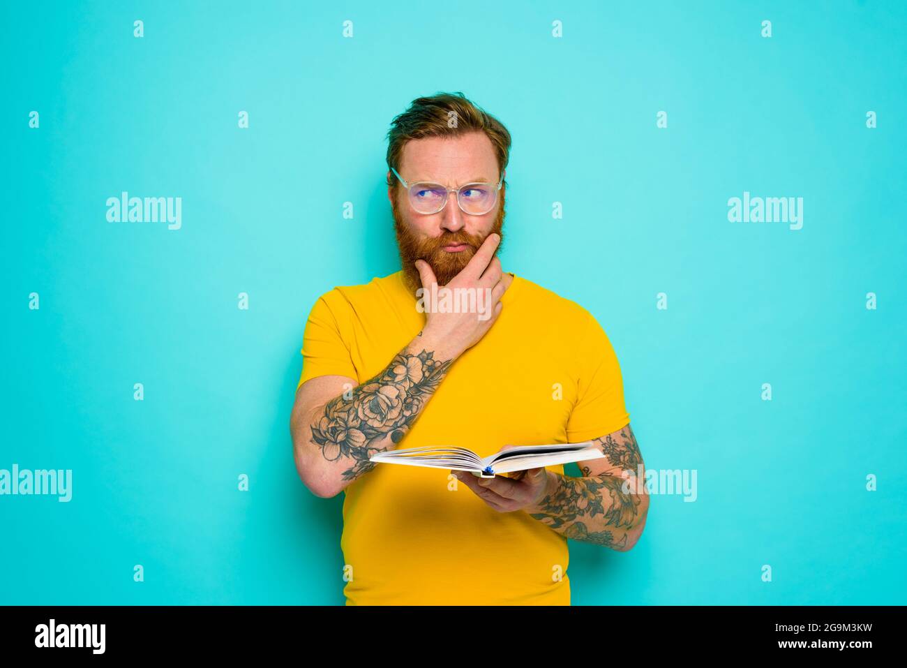 Uomo con t-shirt gialla legge un libro Foto Stock