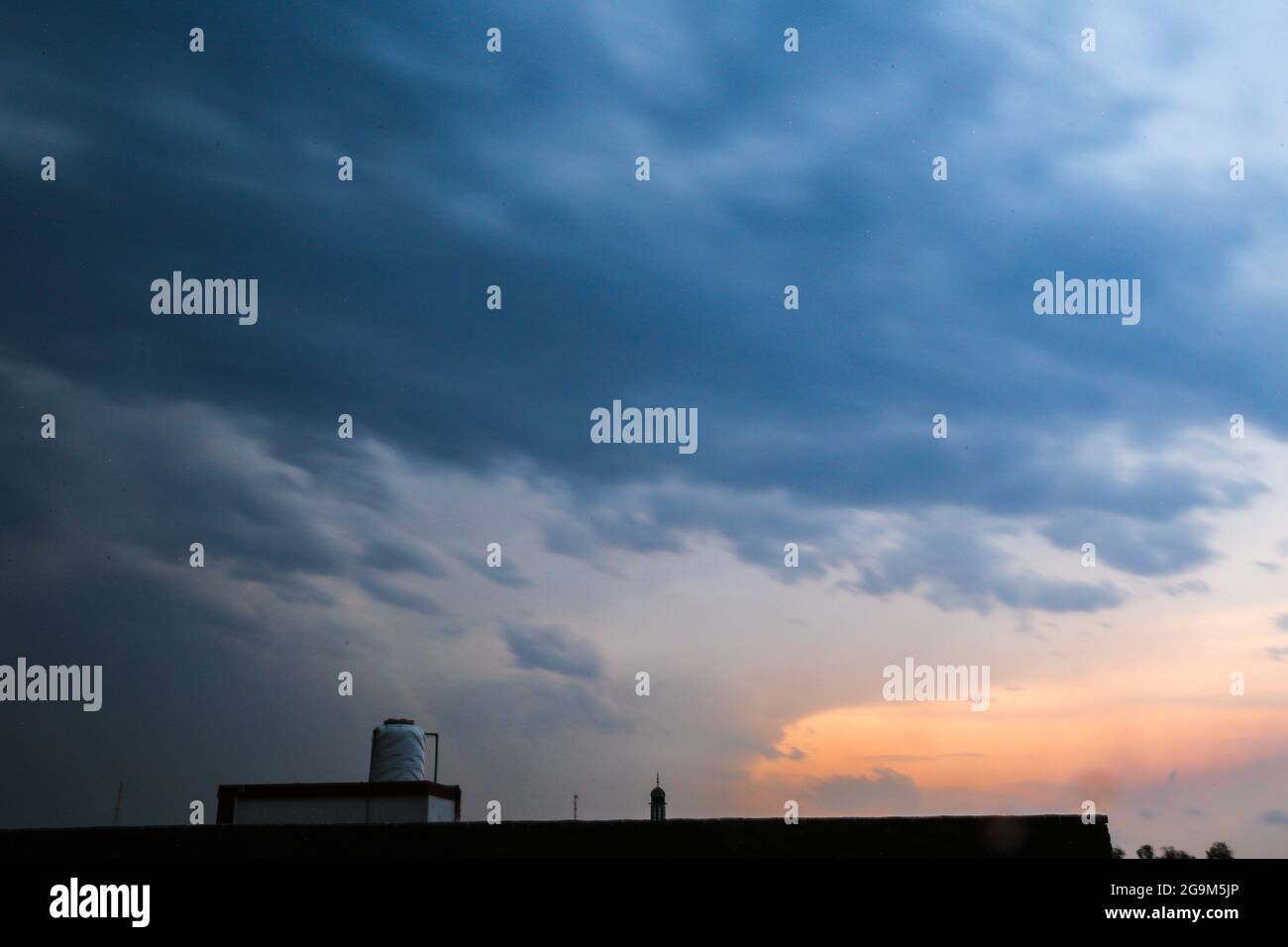 Alba cielo blu drammatico con raggi di sole arancio che si infrangono attraverso le nuvole. Natura sfondo. Concetto di speranza Foto Stock