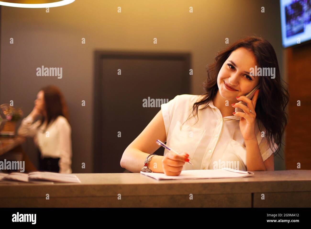 Donna brunette receptionist che lavora alla reception del salone di bellezza Foto Stock