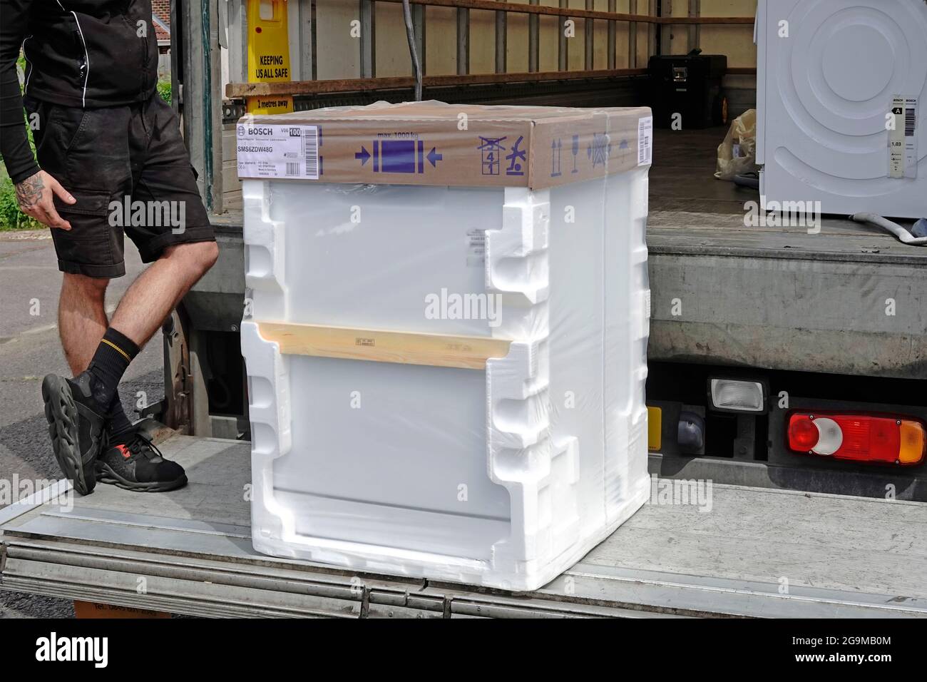 Driver per la consegna a domicilio del grande magazzino John Lewis sul portellone del camion per il nuovo apparecchio per lavastoviglie domestico Bosch White Goods in confezioni in polistirene UK Foto Stock
