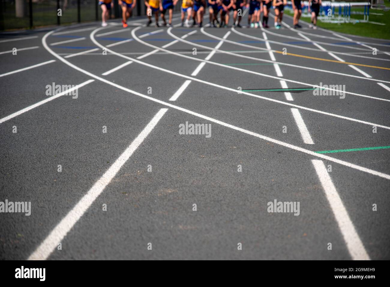 Runner che gareggiano verso la telecamera dalla linea di partenza sul tracciato atletico Foto Stock