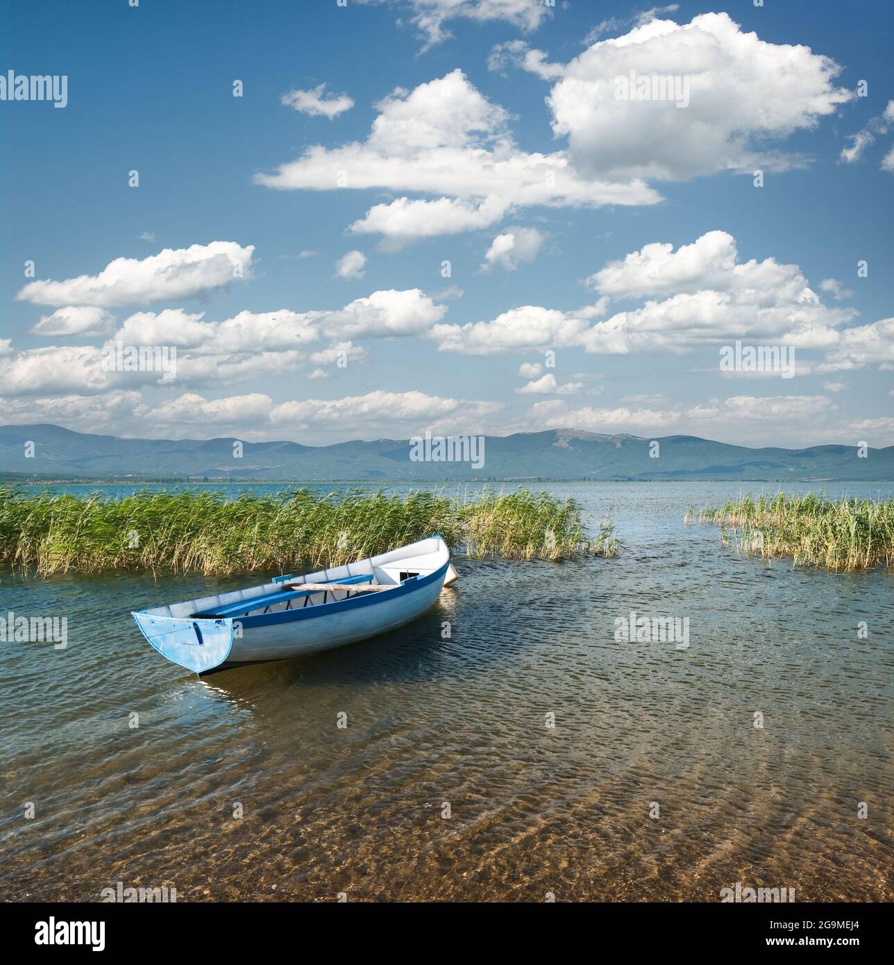 Vista di una barca a remi e cloudscape sul lago Prespa dal lato macedone Foto Stock