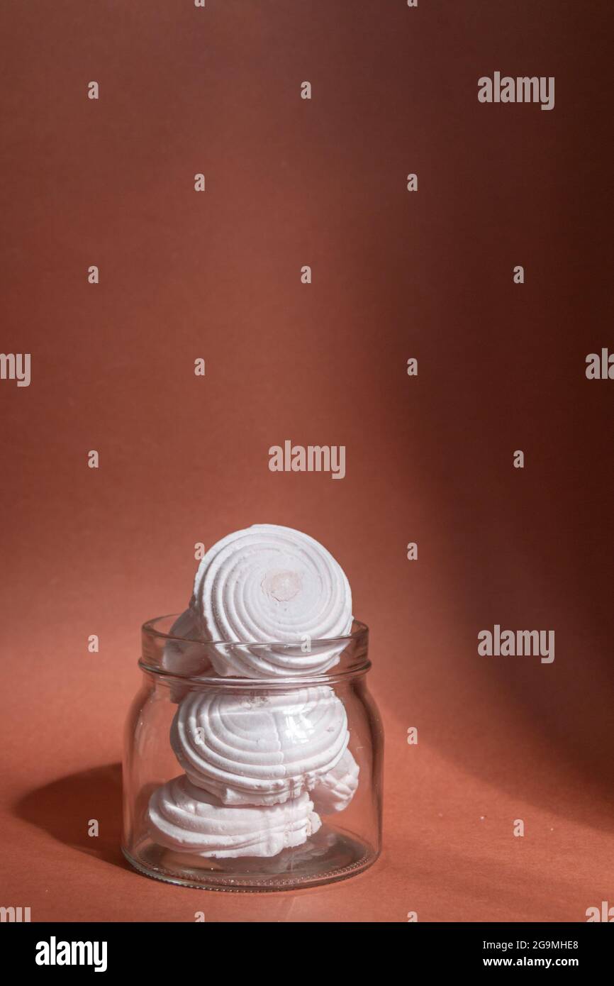 marshmallow rosa in vaso di vetro su sfondo marrone, luce naturale del sole Foto Stock