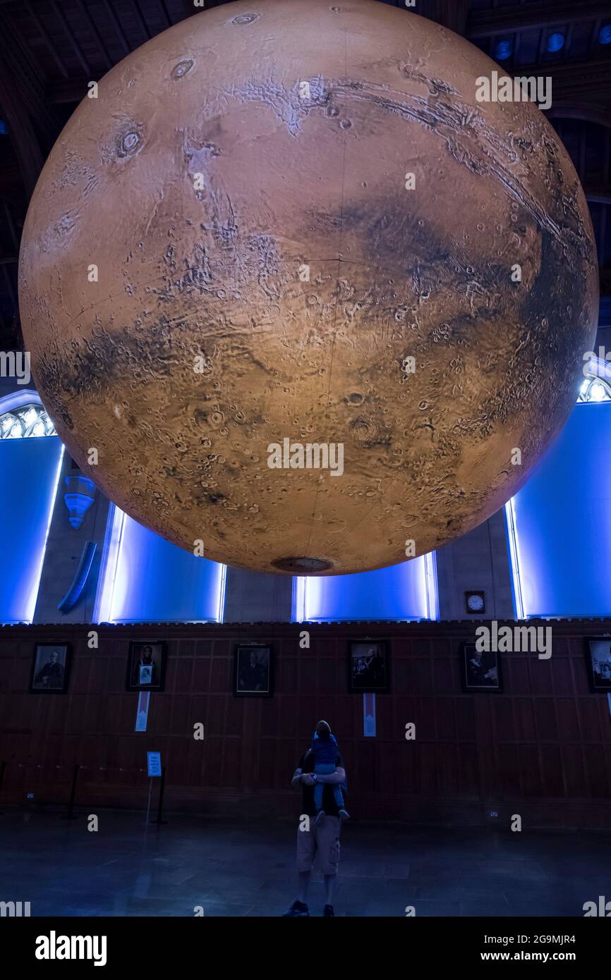 Bristol, Regno Unito. 27 luglio 2021. Luke Jerram mostra il suo modello di Marte di sette metri nella Grande Sala del Wills Memorial Building Bristol University. Utilizzando le immagini della NASA, il modello consente alle persone di vedere le montagne, le valli e i crateri del nostro vicino pianeta Rosso. La mostra sarà aperta al pubblico, al personale e agli studenti dal 27 luglio al 1 agosto. Credit: JMF News/Alamy Live News Foto Stock
