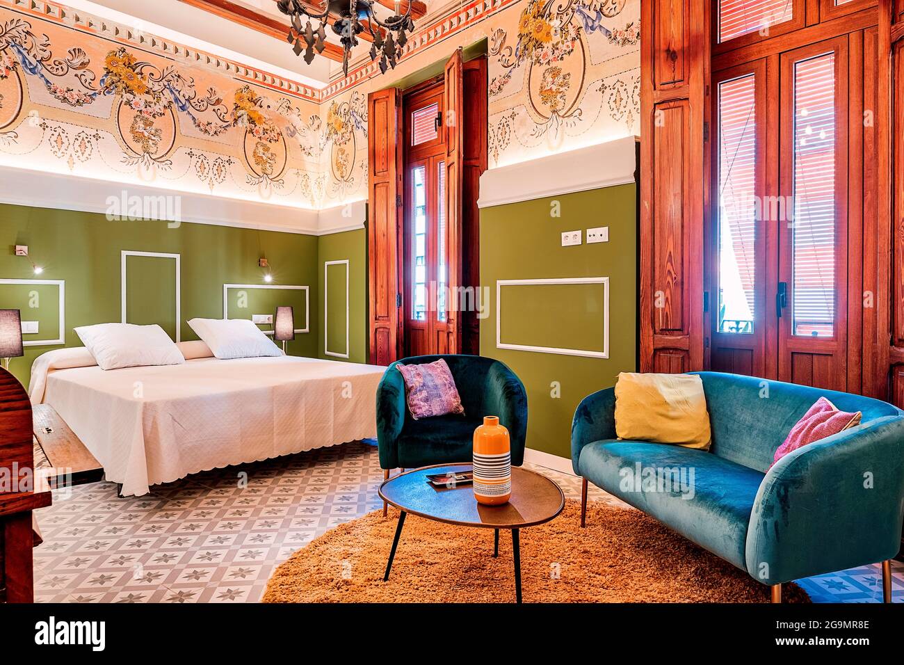 Camera bella e luminosa con decorazioni vintage e vivaci, soffitti alti e finestre in legno fatte a mano. Sfondi e pavimento piastrellato. Foto Stock