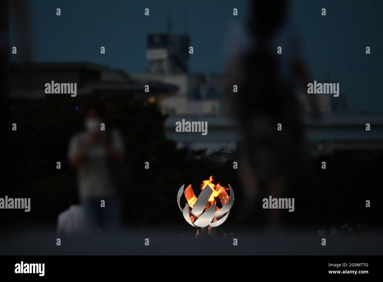 Tokio, Giappone. 27 luglio 2021. Passers-by a piedi passando la fiamma olimpica. Le Olimpiadi di Tokyo 2020 si terranno dal 23.07.2021 al 08.08.2021. Credit: Swen Pförtner/dpa/Alamy Live News Foto Stock