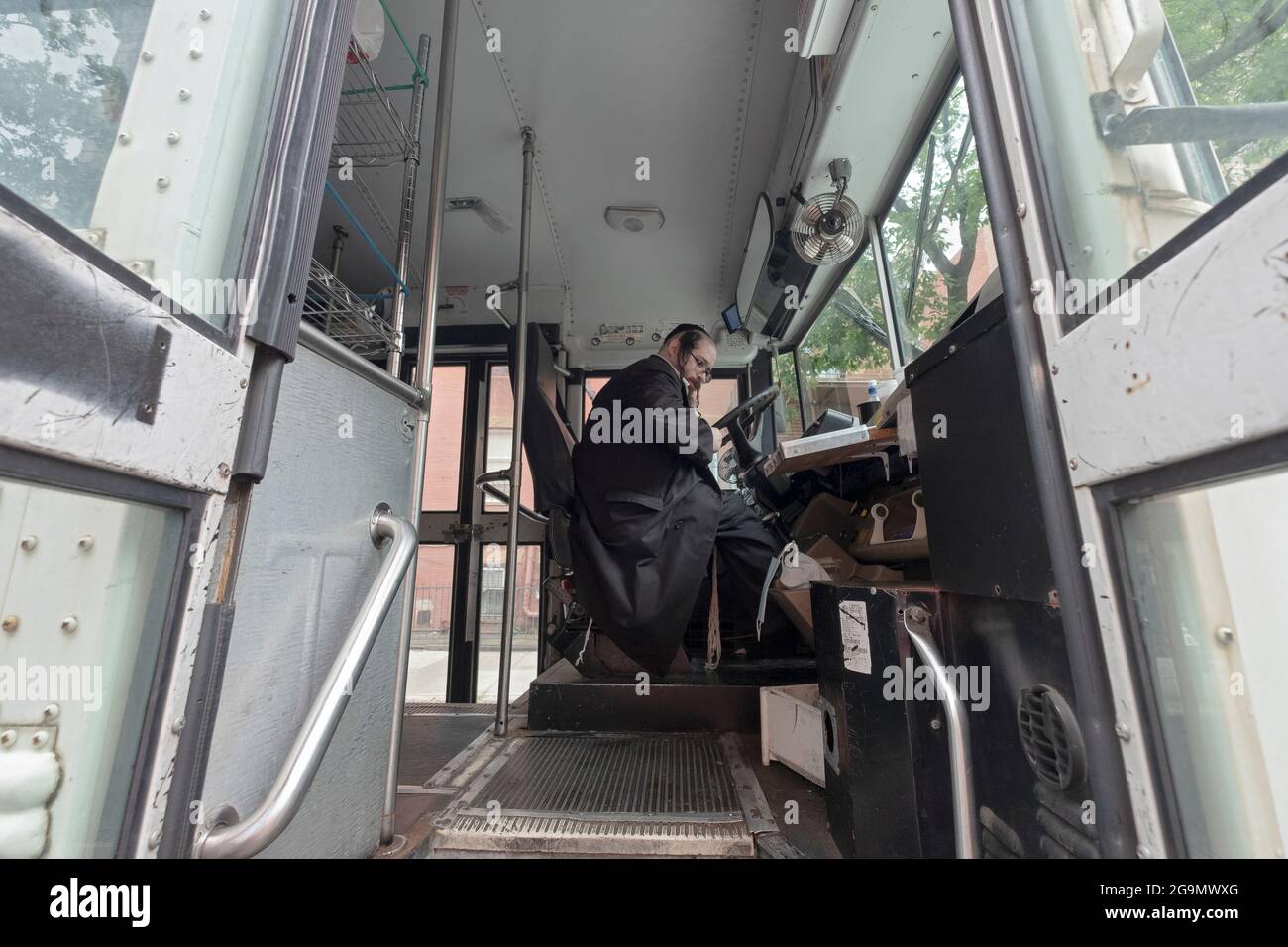 Un ebreo satmar Chassidico si prepara a guidare un autobus con donazioni di cibo per i malati e bisognosi presso gli ospedali locali. A Williamsburg, Brooklyn, New York. Foto Stock