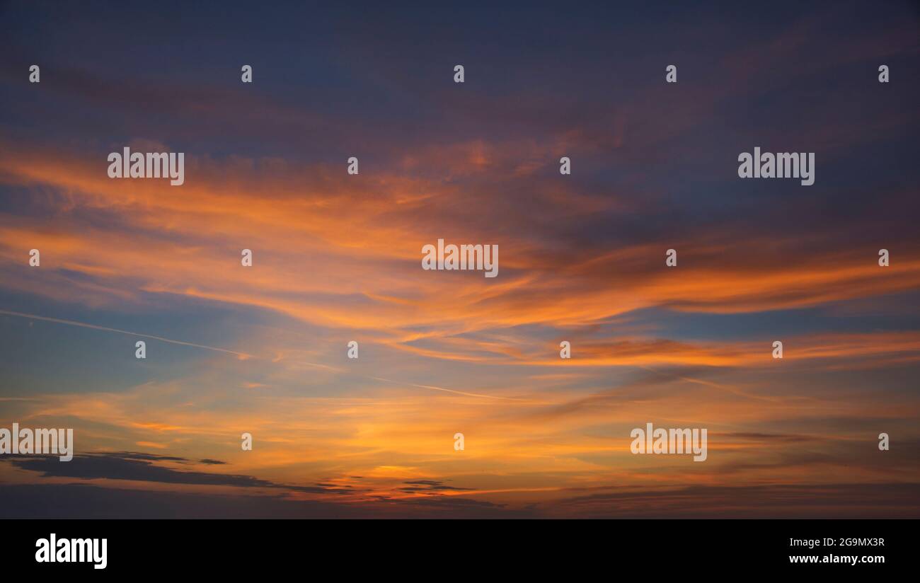 sfondo naturale del sole che tramonta dietro una nuvola e. con raggi solari Foto Stock