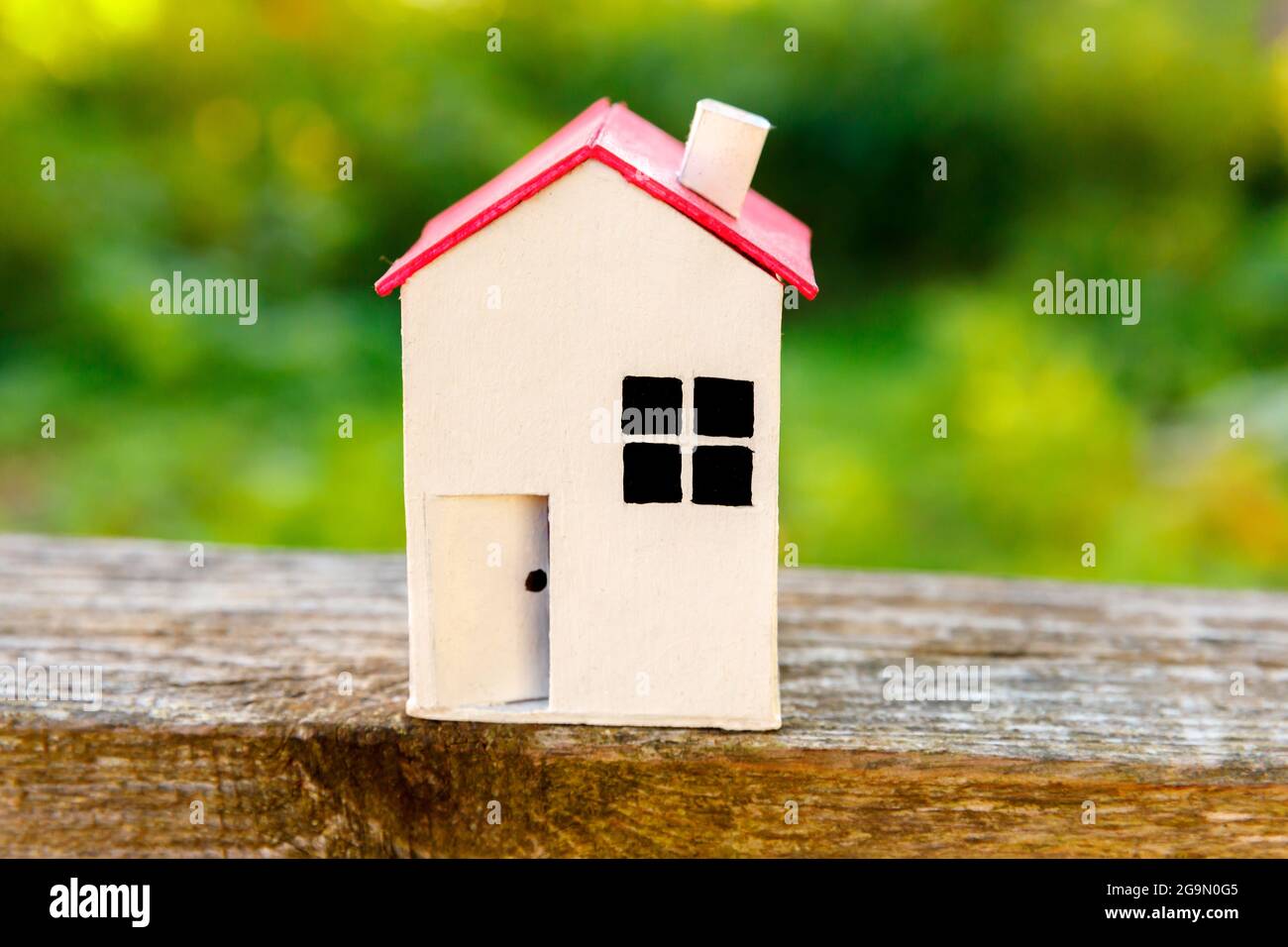 Miniatura bianco giocattolo modello casa su sfondo di legno vicino sfondo verde. Eco Village, astratto contesto ambientale. Ipotecario immobiliare Foto Stock