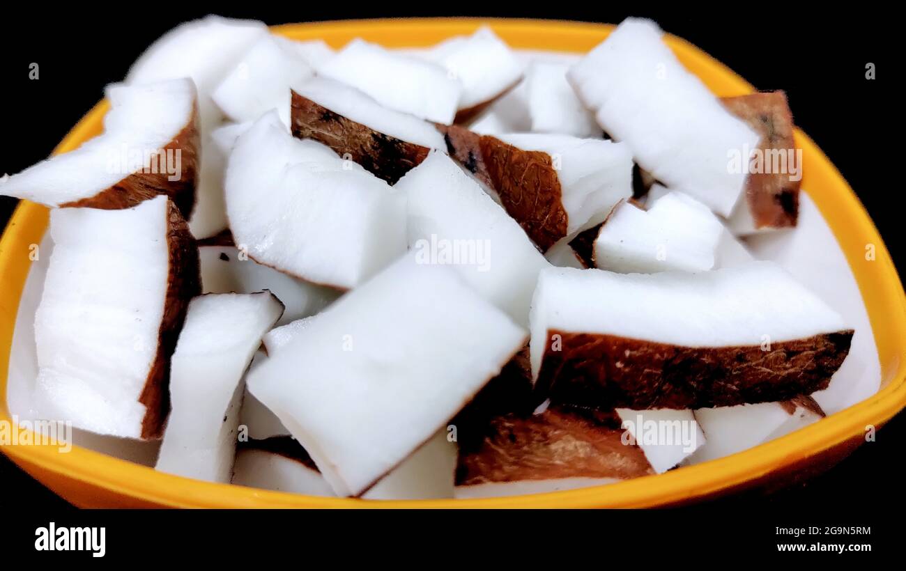 Pezzi di cocco fresco in una ciotola su sfondo di colore scuro con spazio di copia Foto Stock