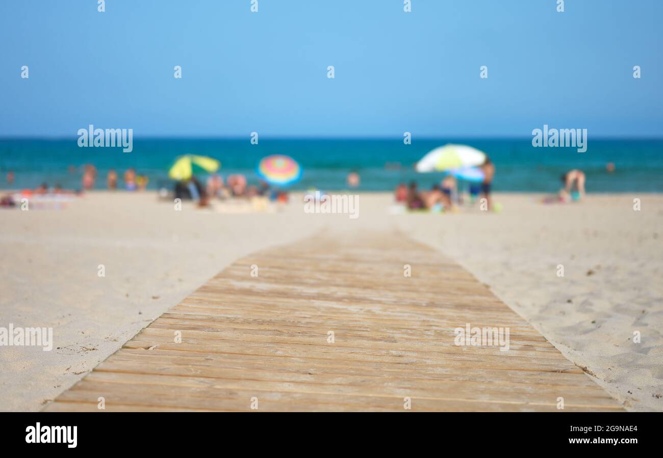 particolare di una passerella in legno su una spiaggia con turisti e ombrelloni con il mare e il cielo sullo sfondo Foto Stock