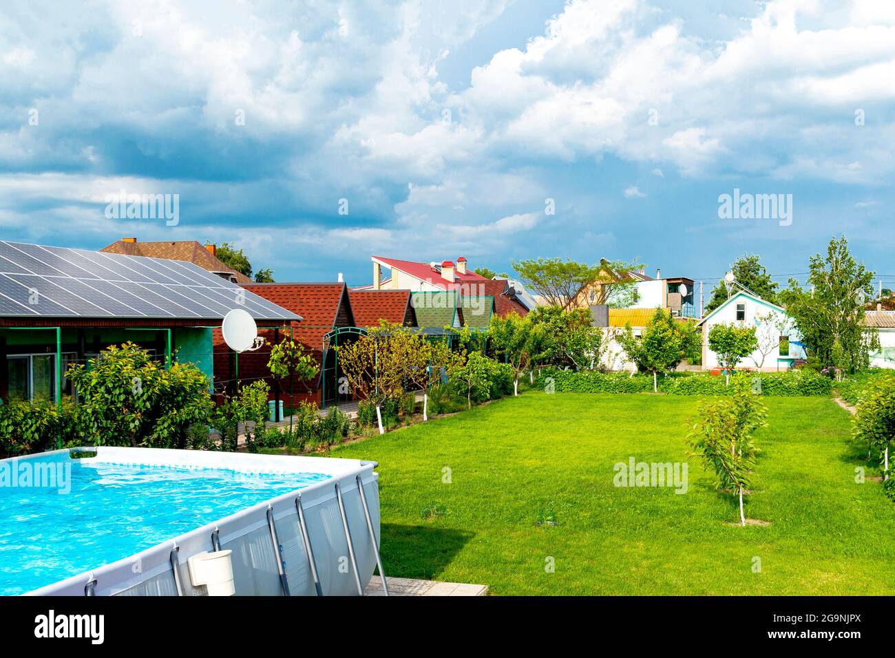 casa con giardino verde erba coperta, pannelli solari sul tetto, piscina con acqua blu Foto Stock