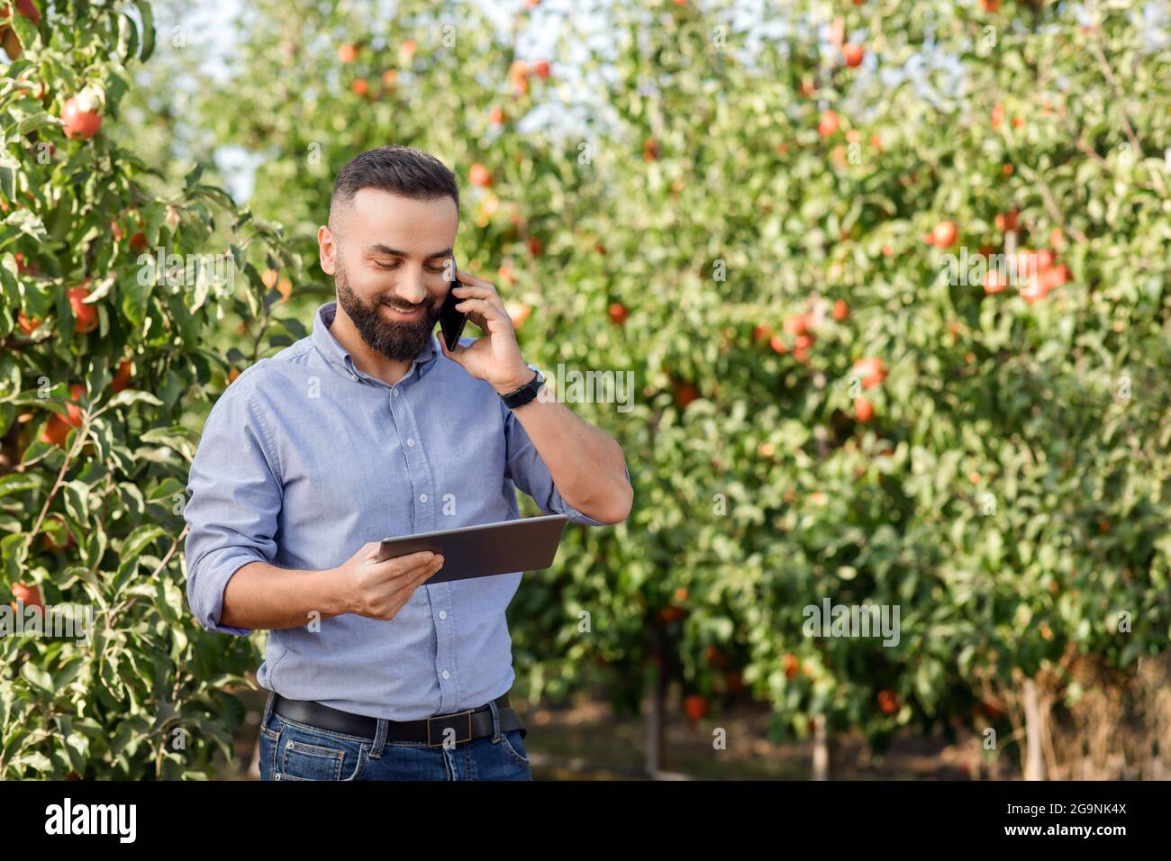 Business moderno, uomo proprietario lavoro in eco fattoria, nuova normale, tecnologia mobile per la coltivazione di frutti biologici Foto Stock