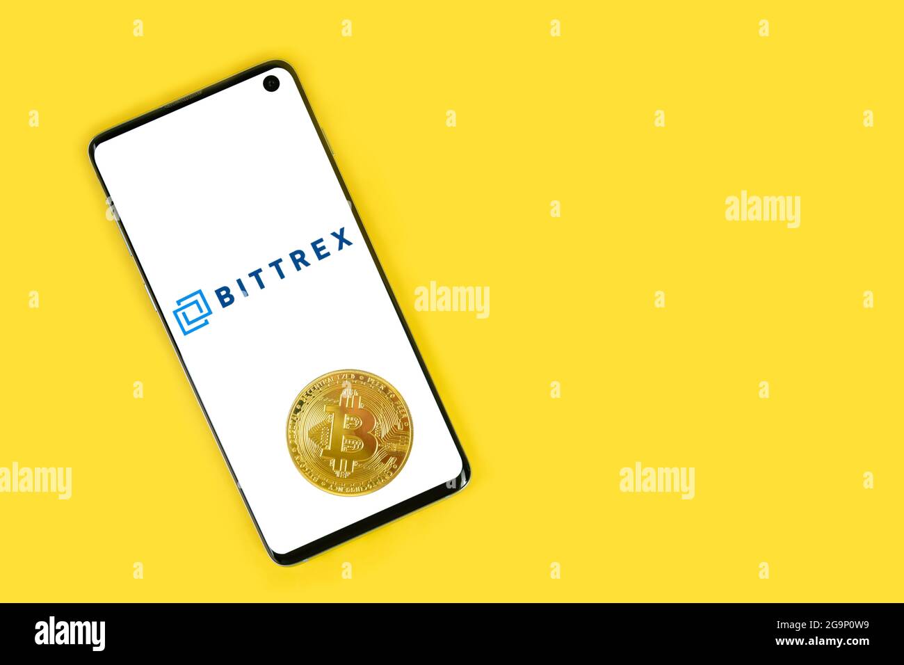SWANSEA, UK - 4 MAGGIO 2021: Smartphone con logo Bittrex con moneta Bitcoin su sfondo giallo. Servizio di pagamento mobile, investendo in criptovalute Foto Stock