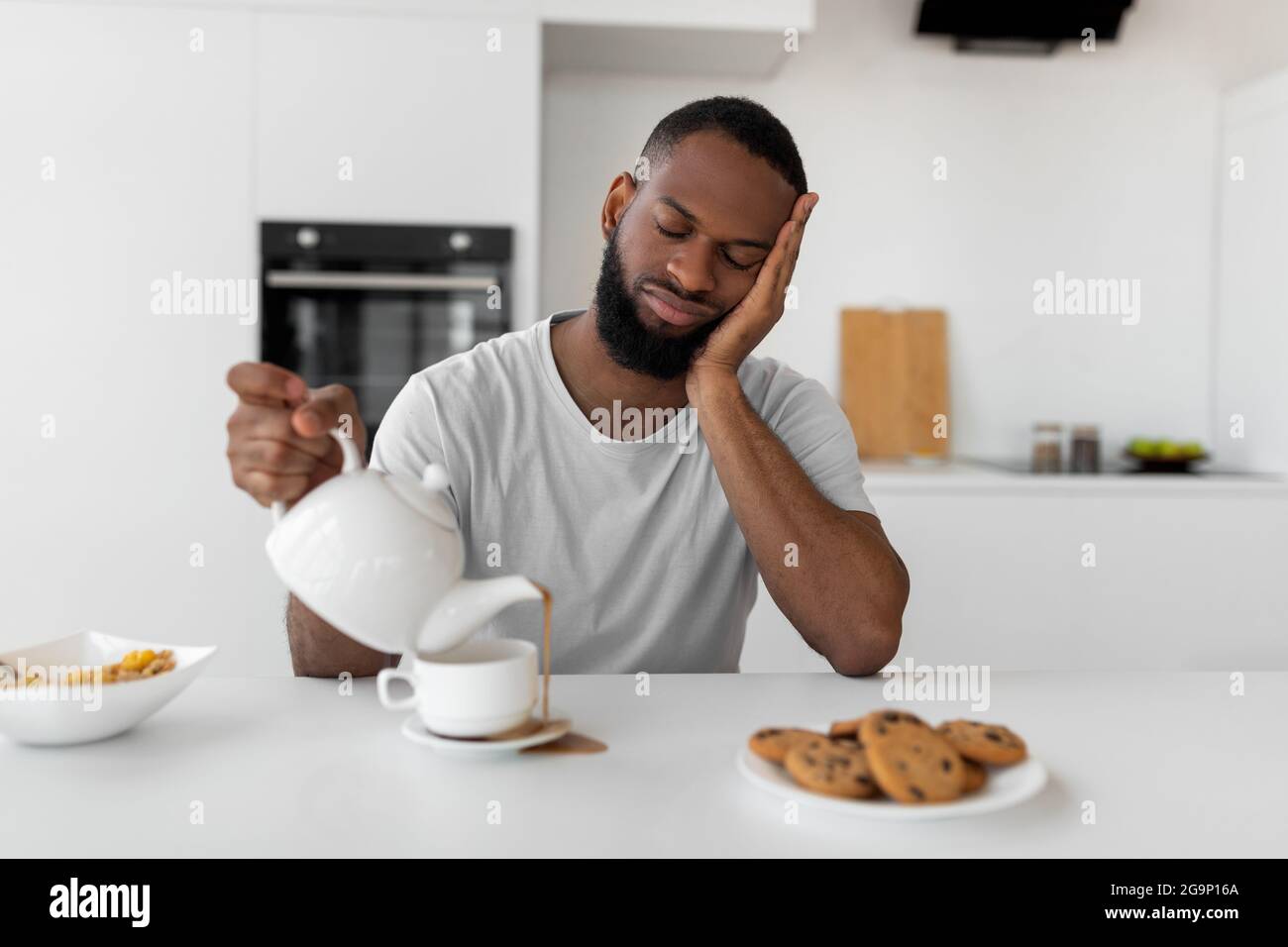 Uomo nero che versa il caffè lontano dalla tazza che versa la bevanda calda Foto Stock