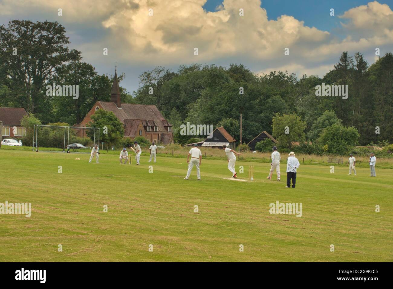 Una tradizionale scena estiva inglese paese - cricket su un villaggio verde - qui a Ockley, Surrey, Regno Unito Foto Stock