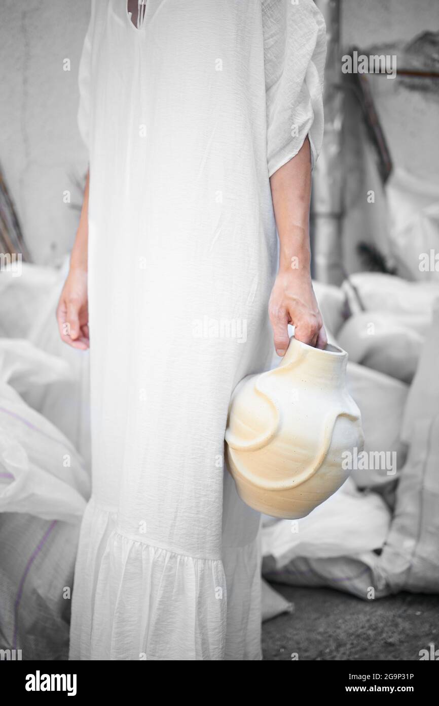 Artista femminile in un vestito tradizionale bianco che tiene la sua opera d'arte Foto Stock