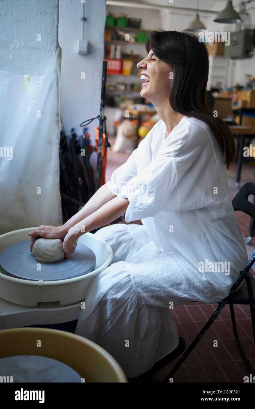 Un artista che sorride e crea su una ruota in ceramica Foto Stock