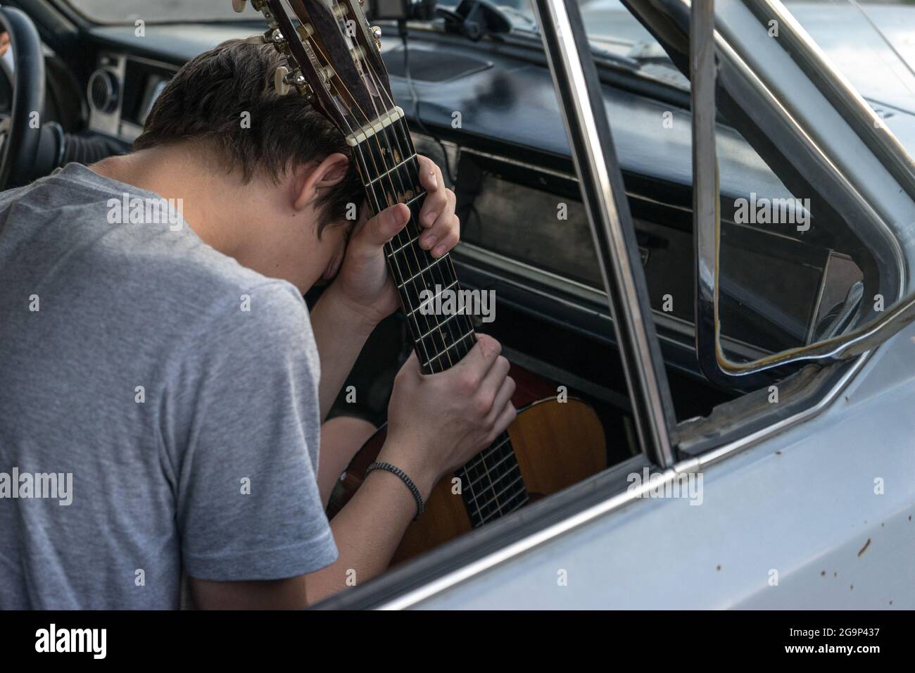 Due giovani in macchina. Il ragazzo suona la chitarra in macchina. Compagnia allegra di giovani. Viaggia insieme. Divertimento passatempo. Foto Stock