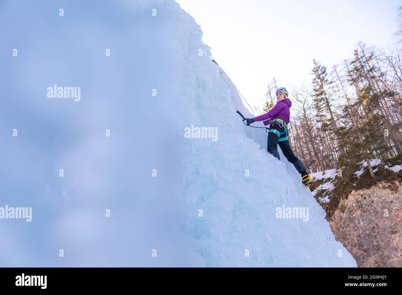 Femmina ghiaccio climber silhouette oscillare assi nel ghiaccio con forza, il ghiaccio frantumato caduta Foto Stock