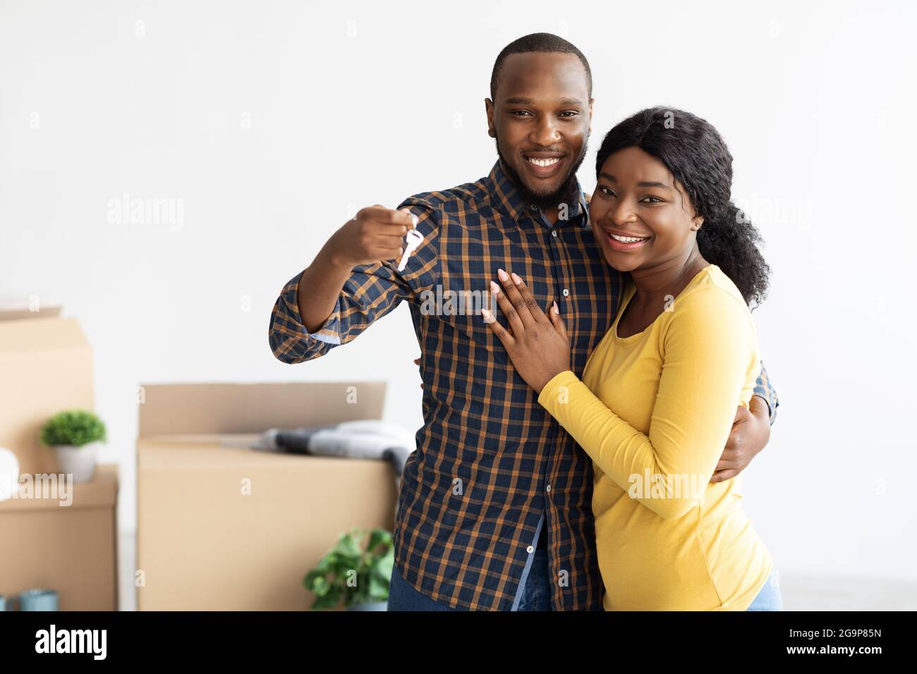 Felici sposi afro-americani che dimostrano le chiavi di casa a macchina fotografica e abbracciare Foto Stock