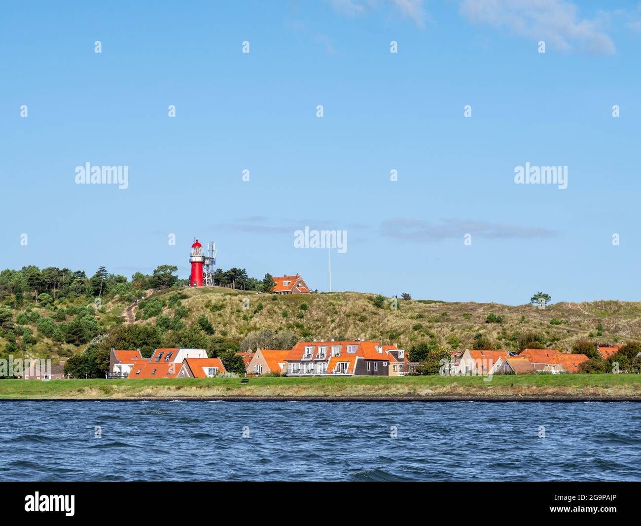 Isola Frisone Ovest Vlieland con faro di Vuurduin su Vuurboetsduin e città di Vlieland Est dal Mare di Wadden, Frisia, Paesi Bassi Foto Stock