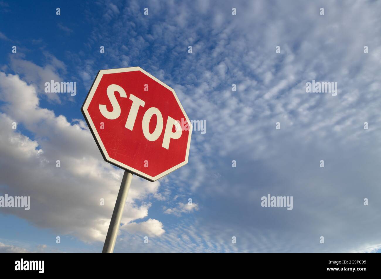 segnale di stop contro il cielo blu e le nuvole bianche Foto Stock
