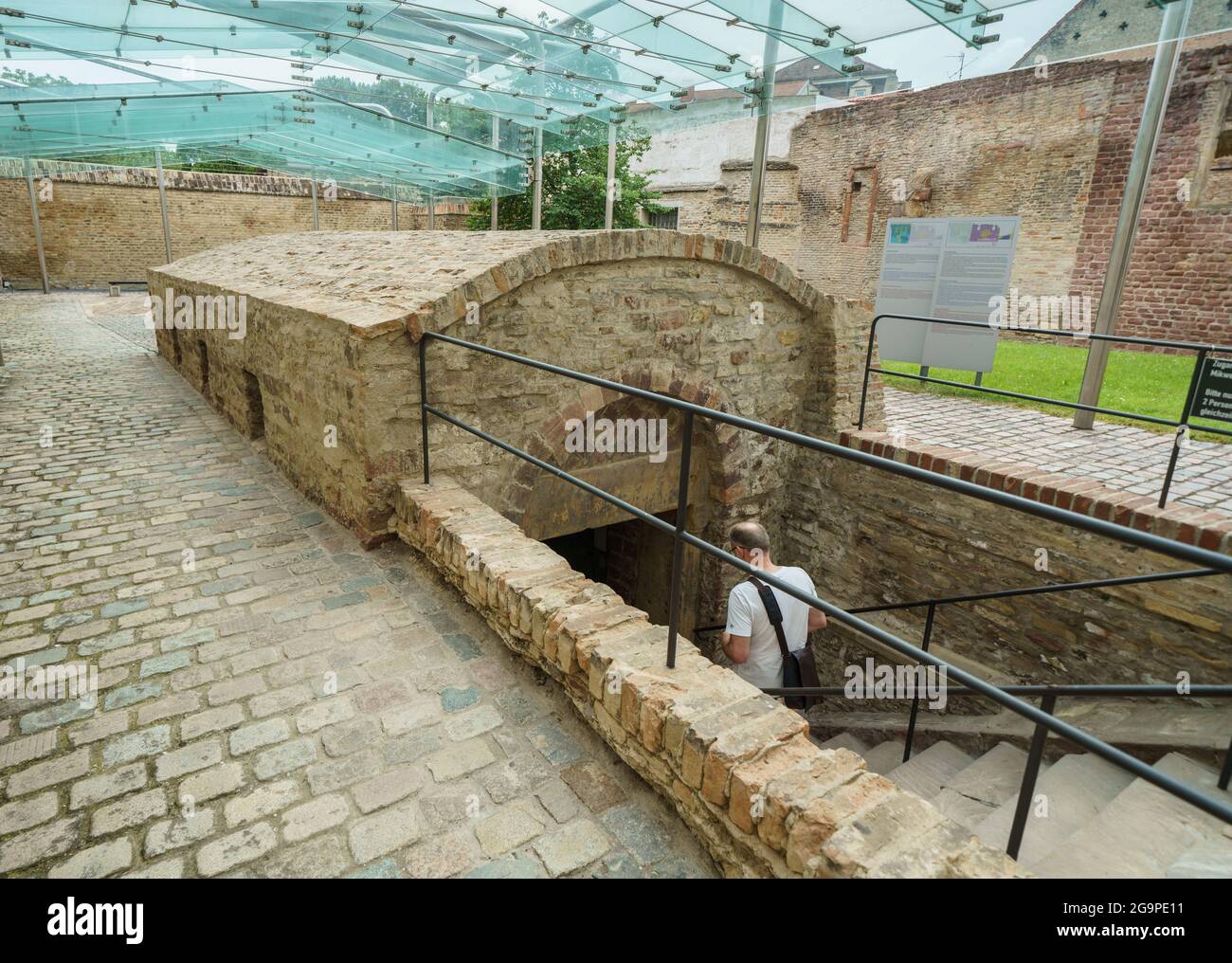 Speyer, Germania. 27 luglio 2021. Un uomo entra nell'edificio della mikvah, che fu costruito nel 1120 in stile architettonico romanico. Il bagno rituale ebraico con una piscina a tuffo a circa dieci metri sotto il livello della strada di oggi nel suo stile architettonico monumentale è considerato il più antico mikvah conosciuto del suo genere. Per la prima volta, l'UNESCO ha designato i beni culturali ebraici in Germania come siti Patrimonio dell'Umanità, con l'ambito premio destinato ai cosiddetti siti Shum di Magonza, Worms e Speyer come culla dell'ebraismo europeo. Credit: Frank Rumpenhorst/dpa/Alamy Live News Foto Stock