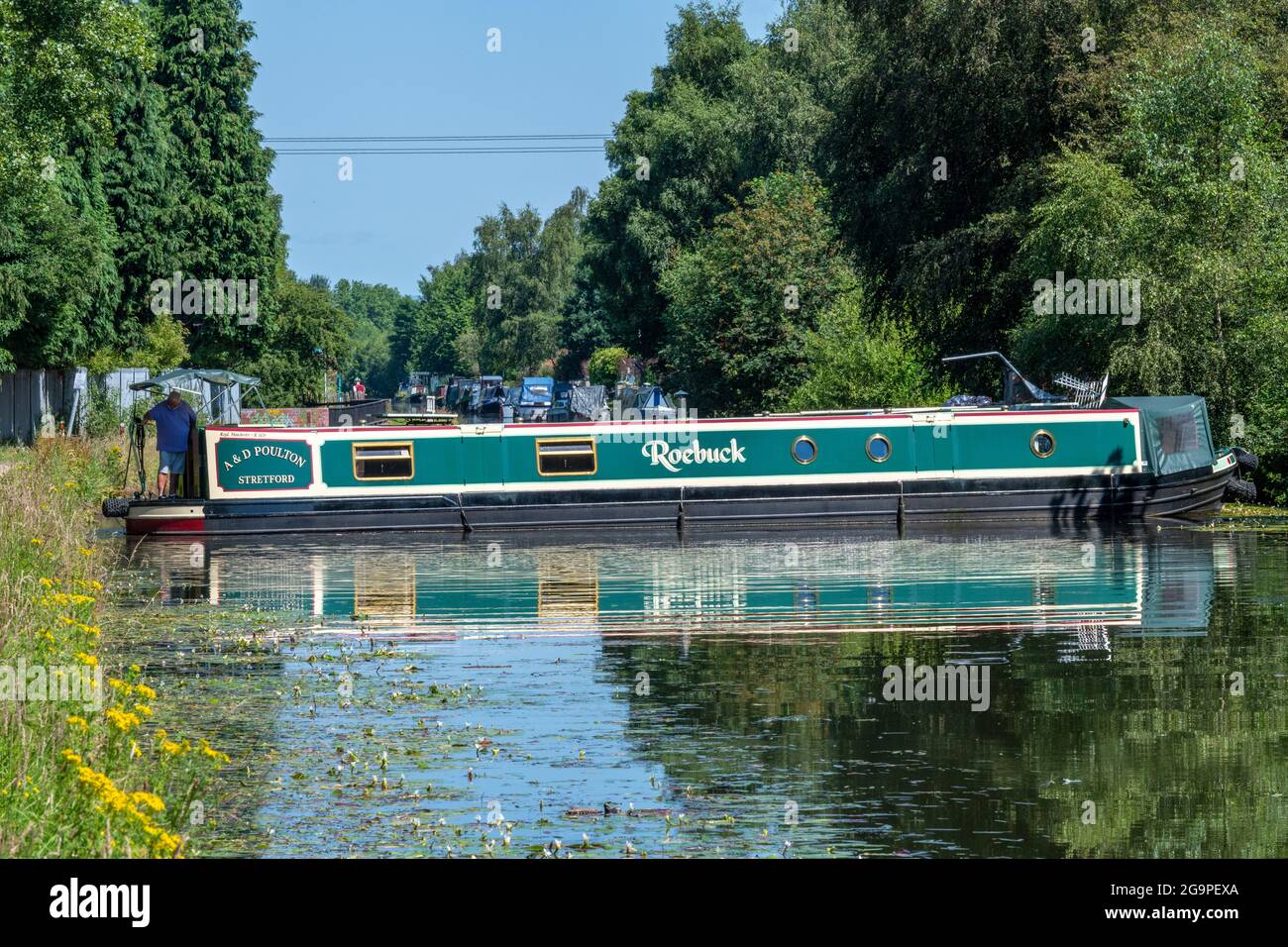 uomo che guida al timone di un narrowboat tradizionale o chiatta sul canale bridgewater in vendita, greater manchester, regno unito Foto Stock