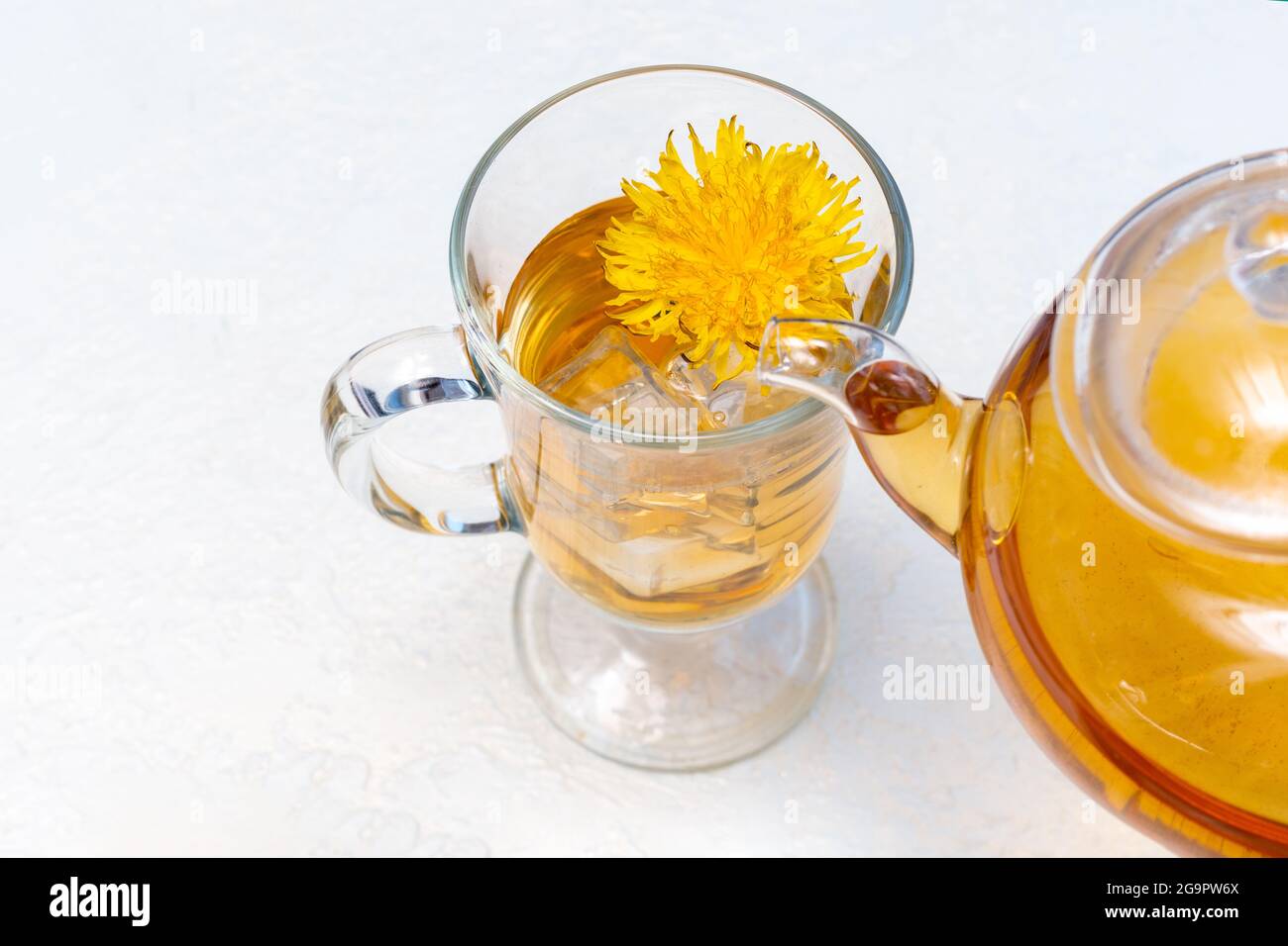 Versare il tè al dente di leone alle erbe in una tazza trasparente da una  teiera
