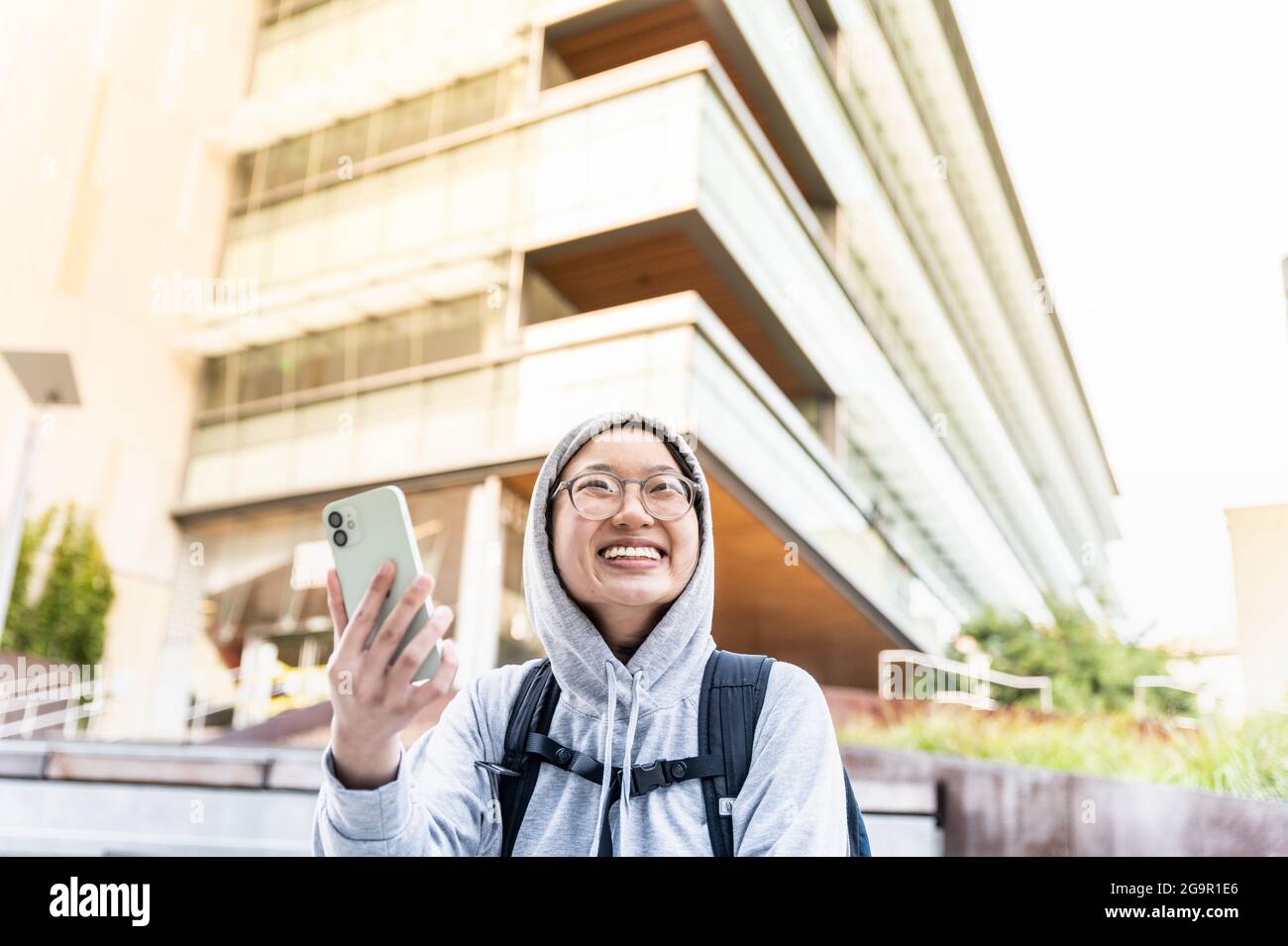 Giovane asiatico con smartphone sorridente in centro Foto Stock