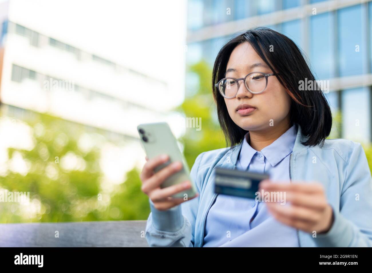 Giovane adulto asiatico che utilizza la carta di credito per effettuare l'acquisto su smartphone Foto Stock