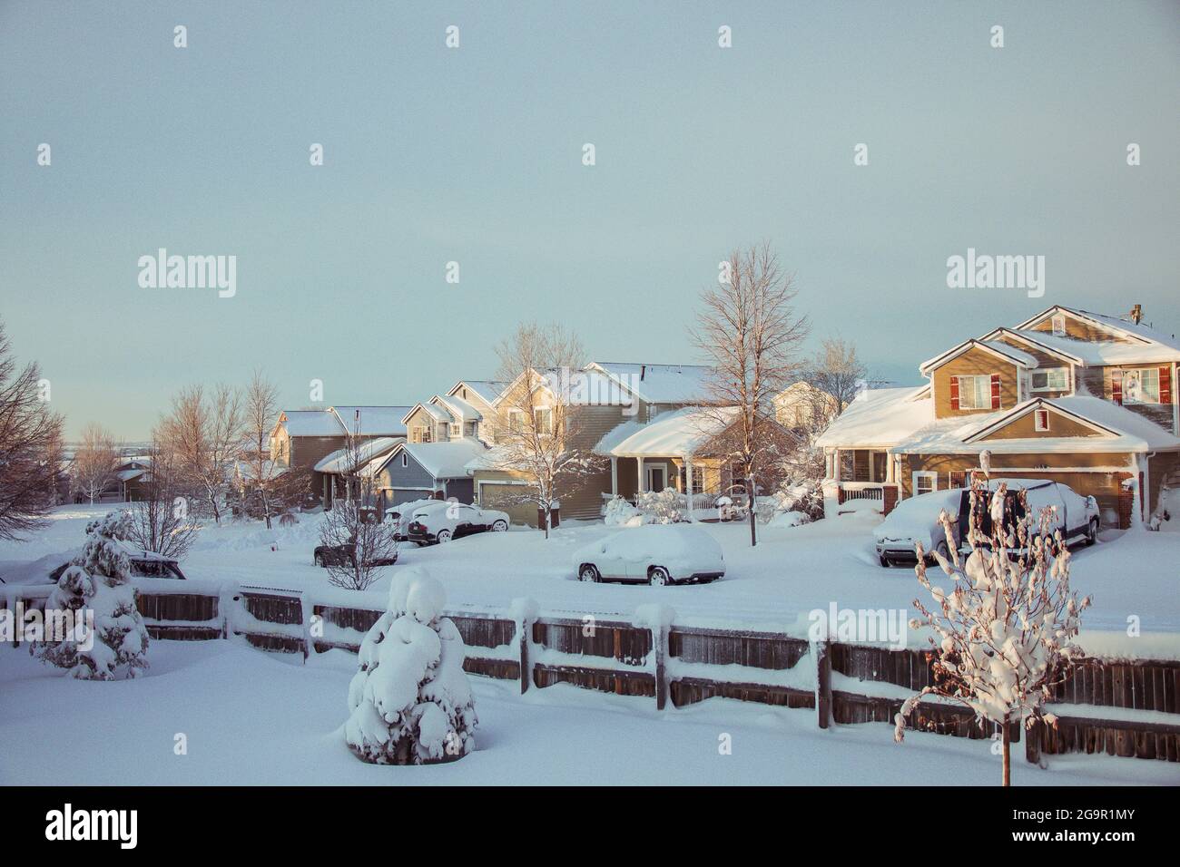 Un quartiere in inverno con le auto coperte da neve. Case e alberi Foto Stock