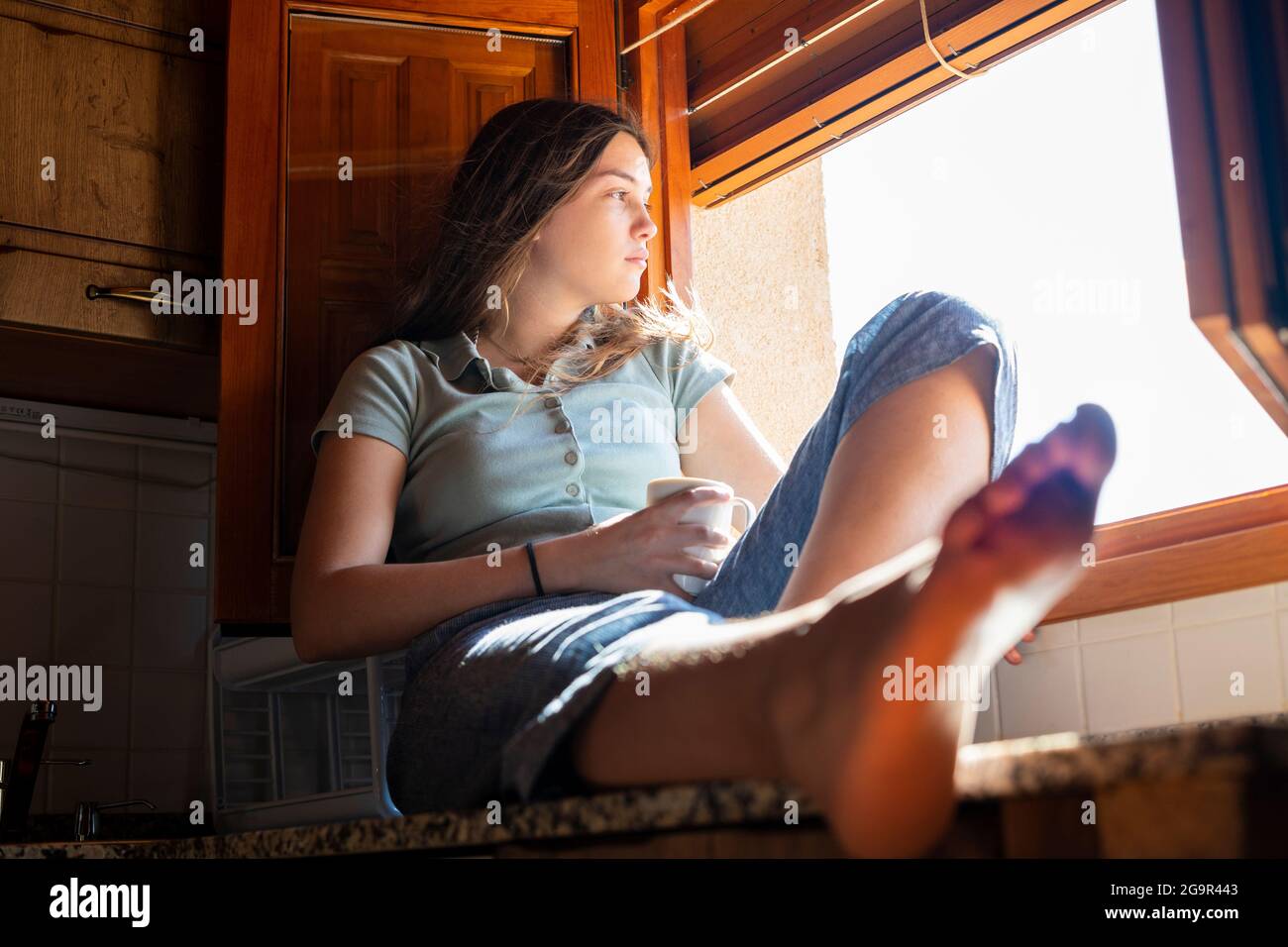 Adolescente donna seduta guardando fuori la finestra. Foto Stock