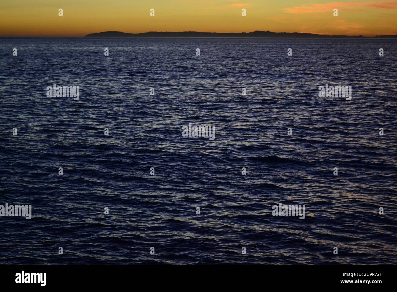 Onde di mare di colore pesante durante il tramonto. La luce scarsa e la granulosità donano una texture rilassante alla foto. Foto Stock