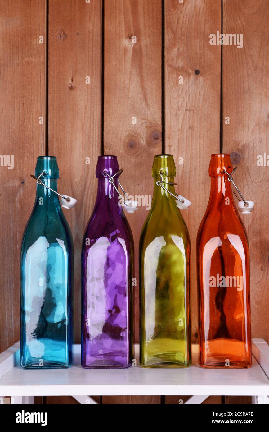 Design interno con bottiglie di vetro colorate su piano del tavolo su  sfondo di tavole di legno Foto stock - Alamy
