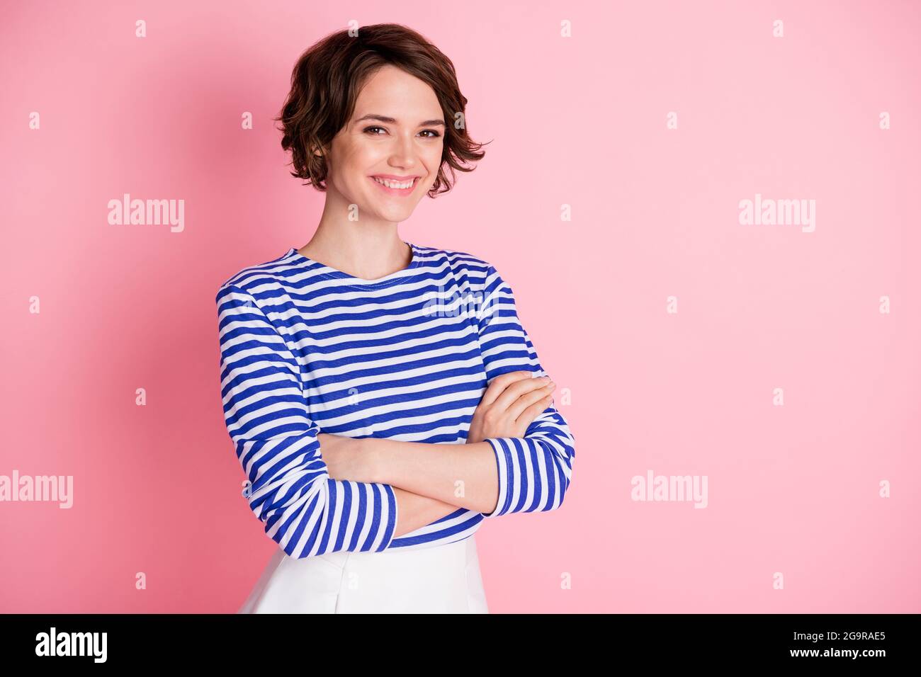 Foto di giovane bella sorridente allegra ragazza positiva con le braccia ripiegate guardare fotocamera isolata su sfondo di colore rosa Foto Stock