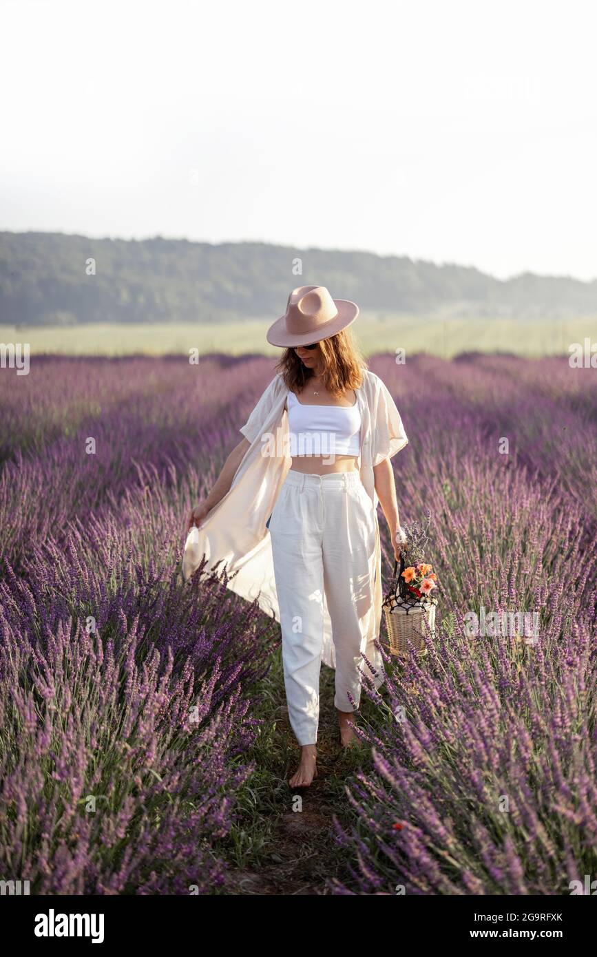 Giovane donna che cammina sul campo di lavanda con bouquet di fiori viola e godere della bellezza della natura. Calma e concetto di consapevolezza. Spazio di copia Foto Stock
