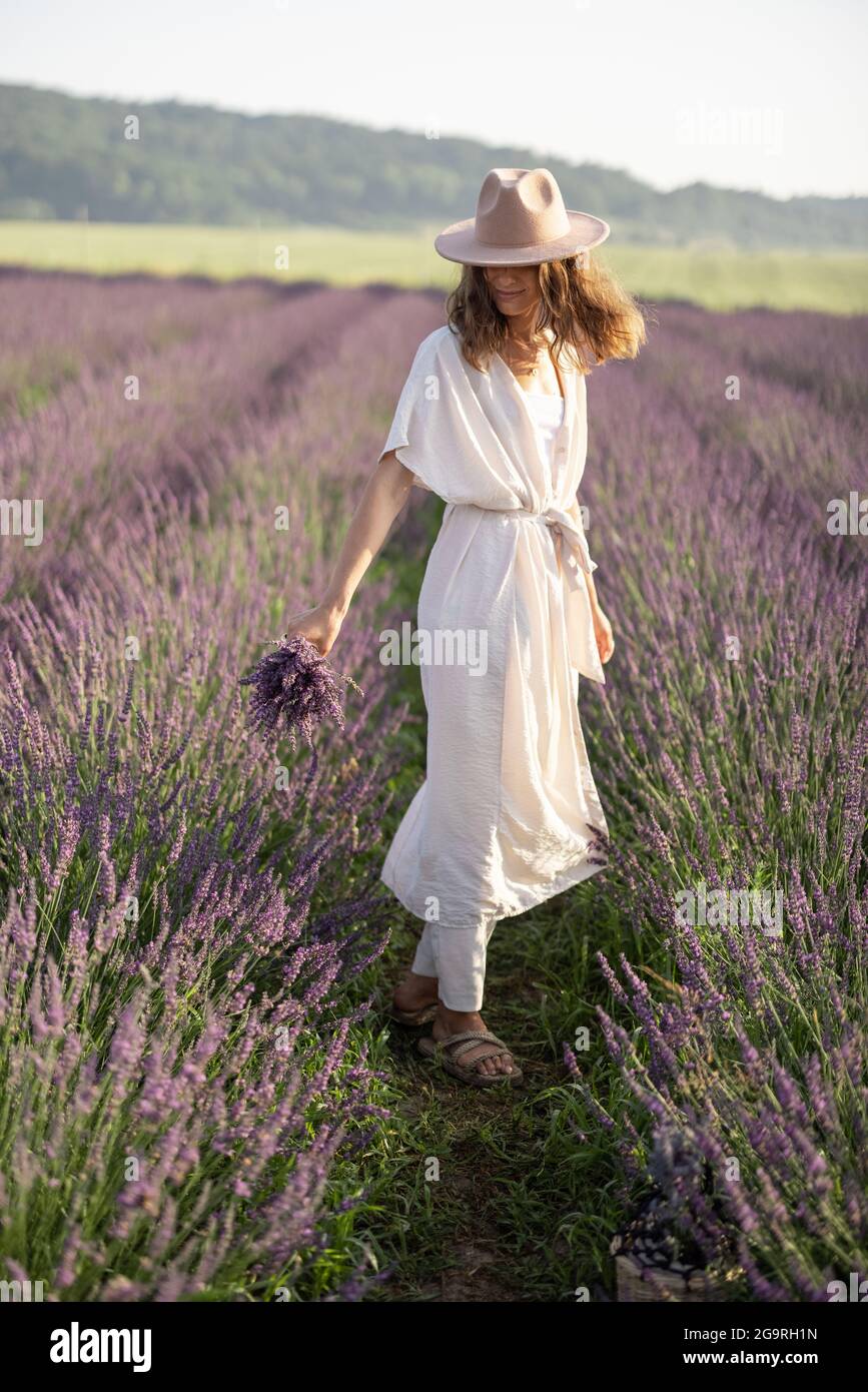 Giovane donna che balla sul campo di lavanda con bouquet di fiori violetti e godere della bellezza della natura. Calma e concetto di consapevolezza Foto Stock