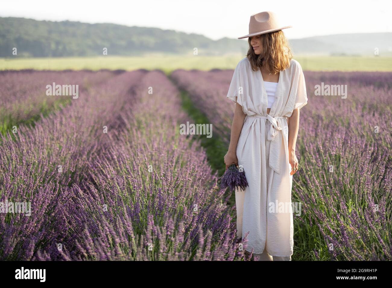 Giovane donna che si trova sul campo di lavanda con bouquet di fiori viola e godere della bellezza della natura. Calma e concetto di consapevolezza. Spazio di copia Foto Stock
