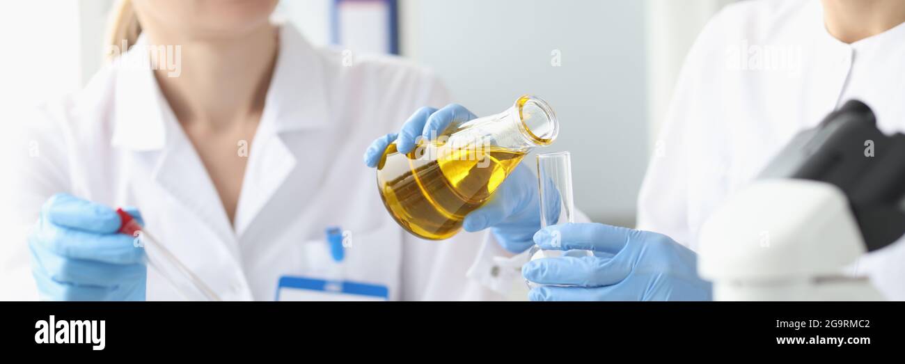 Due ricercatori in laboratorio esaminano il liquido dorato nella provetta Foto Stock